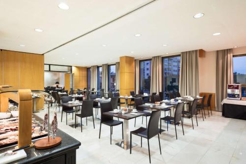 赫罗纳Best Western Premier CMC Girona的餐厅设有桌椅和窗户。