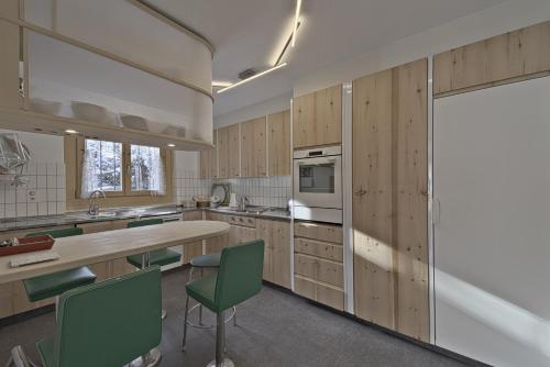 萨梅丹Chesa Chavriol - Samedan的厨房配有木制橱柜和绿色椅子