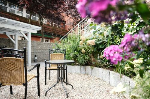 什未林Apartments zur alten Konditorei的庭院配有两把椅子和一张桌子,种有鲜花
