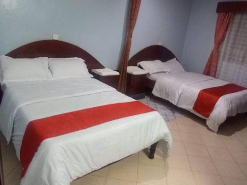 MeruGreton Holiday Villa的酒店客房带两张红色和白色的床单