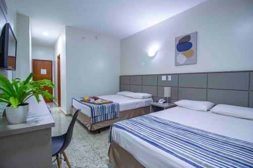 里贝朗普雷托Hotel Vilage Inn Ribeirão Preto & Convenções的酒店客房设有两张床和一张桌子。