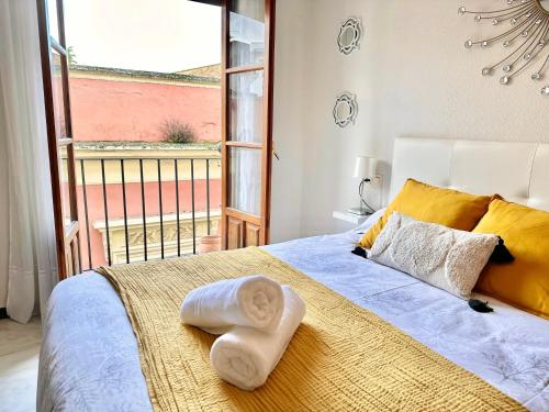 科尔多瓦Ático dúplex centro Córdoba的一间卧室配有一张带黄色枕头的床和一扇窗户
