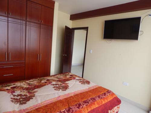安巴托Comodo y centrico的一间卧室配有一张床和一台平面电视