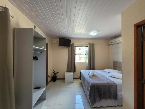 佩尼亚Pousada Pontal da Armação的一间卧室设有一张床,天花板上配有电视。