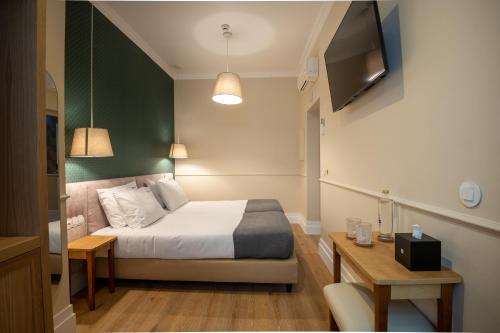 里斯本Rossio FLH Suites的一间卧室配有一张床、一台电视和一张桌子