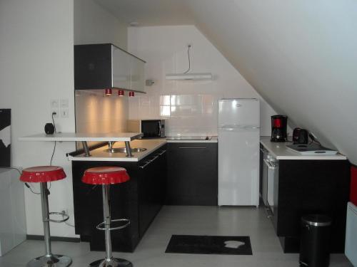 格朗维尔Les granvillaises的厨房配有黑白电器和红色凳子
