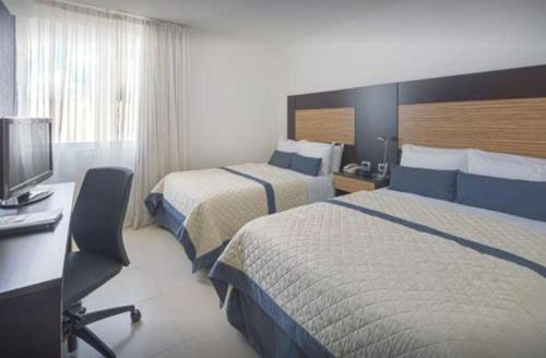 锡劳Hotel México Plaza Silao Aeropuerto的酒店客房设有两张床、一张桌子和一台电视。