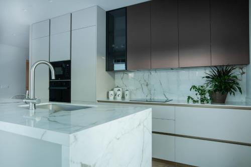 阿基欧斯尼古拉斯Celine Luxury Apartments & Suites的白色的厨房配有水槽和黑色橱柜