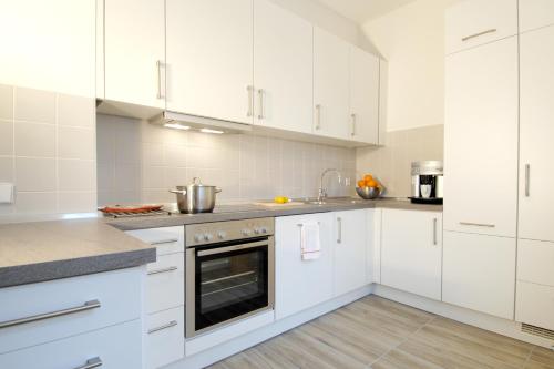 柏林斯塔维拉公寓的白色的厨房配有白色橱柜和电器