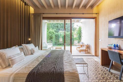 Puig D’en VallsHotel Rural Xereca的一间卧室设有一张大床和一个滑动玻璃门