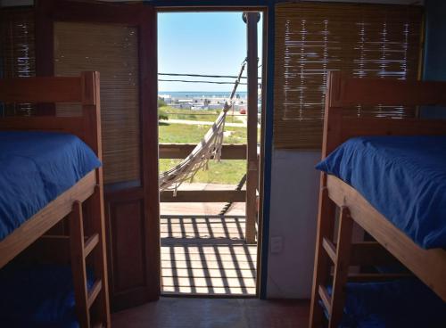 德尔迪阿布罗角Mar de Fondo Hostel的客房设有两张双层床和通往门廊的门。