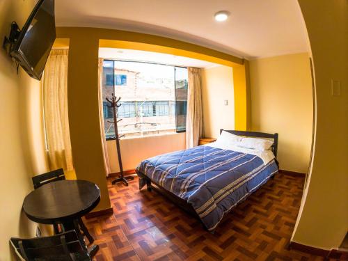 阿亚库乔Hotel Sol de Oro Ayacucho的一间卧室配有一张床、一张桌子和一个窗户。