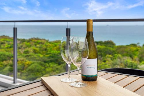 卡瓦纳华特斯Absolute Beachfront 3 Bedroom Penthouse Bokarina Sunshine Coast的桌子上放有一瓶葡萄酒和两杯酒