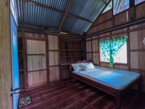 沙璜Cafe Sabang Guest House的木制客房内的一间卧室,配有一张床