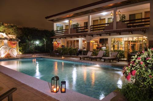 圣何塞La Sabana Hotel Suites Apartments的夜间在房子前面的游泳池