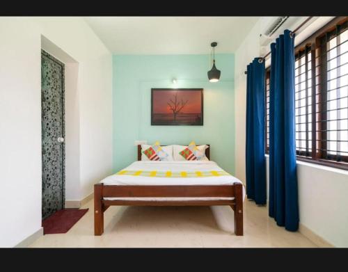 科钦Tharayil Apartments的一间设有床铺的卧室,位于带蓝色窗帘的房间