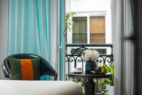 河内Hanoi L'Heritage Hotel & Gym - Spa的阳台配有一张床和一张花瓶桌子