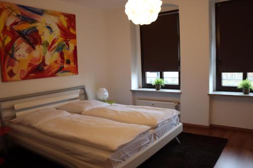 开姆尼茨alexxanders Apartments & Studios的一张位于带两扇窗户和一幅画的房间的床位