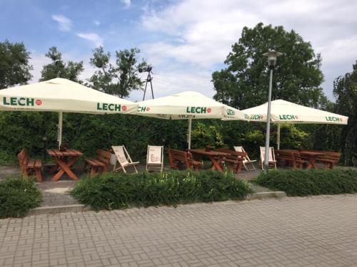 格涅夫Hotel Na Wzgórzu的公园里的一套桌子和遮阳伞