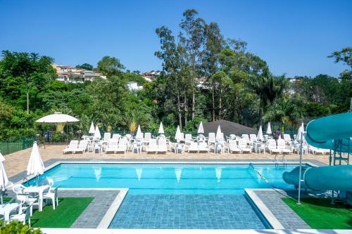 阿蒂巴亚Atibaia Residence Hotel & Resort的一个带白色椅子和滑梯的游泳池
