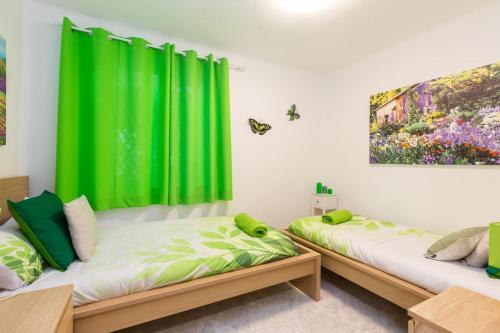 马德里Apartamento Casa de Campo的绿窗帘间内的两张床
