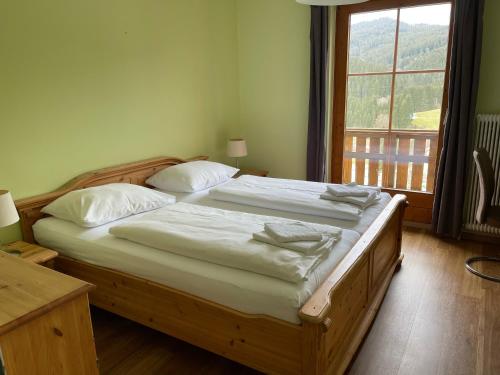 拉肯霍夫Hotel Ötscherblick的一间卧室配有一张带白色床单的木床和窗户。