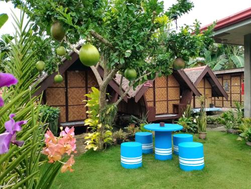 BatuanLHOYJEAN Garden Hostel的一座花园,位于一座房子前面,有树和蓝色的凳子