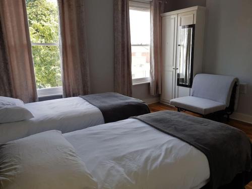 伦敦London. Gorgeous 2 bed flat near Olympic Park.的一间卧室设有两张床、一把椅子和一个窗户。