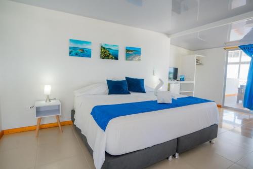 普罗维登西亚Hotel El Pirata Morgan的白色卧室配有一张带蓝色枕头的大床