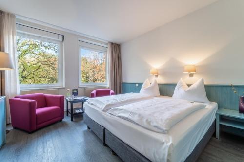 汉堡Auszeit Hotel Hamburg的一间卧室配有一张大床和一张粉红色的椅子