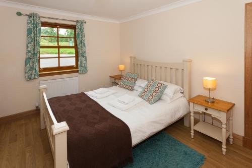 林利斯戈Honeysuckle Cottage at Williamscraig Holiday Cottages的一间卧室设有一张大床和一个窗户。
