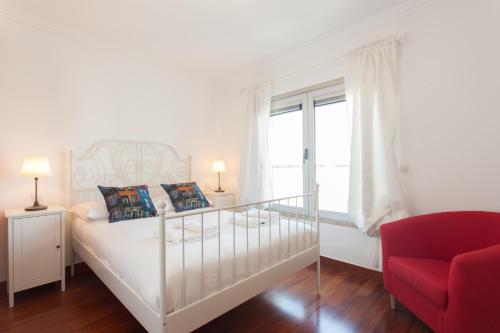里斯本FLH Expo Cozy Apartment的白色卧室,配有床和红色椅子