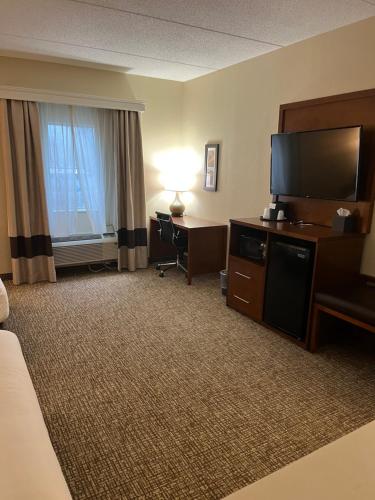 西米夫林Wingate by Wyndham Pittsburgh West Mifflin的酒店客房配有一张床、一台电视和一张书桌。