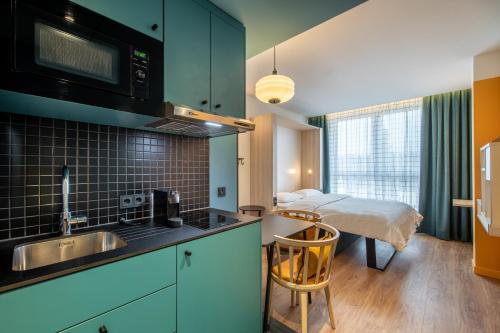 汉堡Aparthotel Adagio access Hamburg的一个带水槽的厨房和一张位于客房内的床