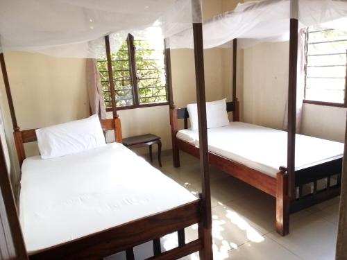 蒙巴萨Cingaki Hotel的带三张双层床和两扇窗户的房间