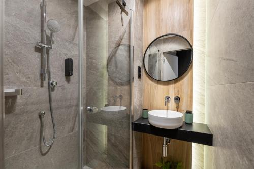 罗兹Luxury Copper Apartment II的带淋浴、盥洗盆和镜子的浴室