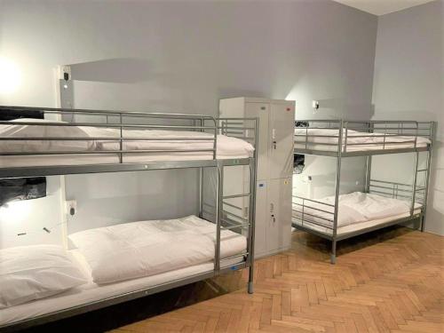 布拉格GLOBE Hostel Prague ADULTS ONLY的客房设有三张双层床,配有白色床单