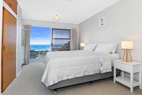 怀普Surfers Lookout - Waipu Cove Holiday Home的白色的卧室设有一张大床和一个窗户