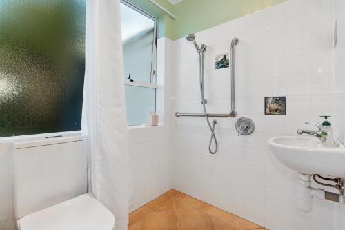 怀普Surfers Lookout - Waipu Cove Holiday Home的带淋浴和盥洗盆的白色浴室