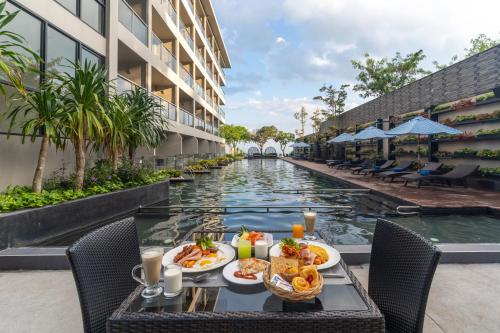 北芭堤雅芭堤雅金色郁金香海滩度假酒店的一张桌子,旁边是酒店的游泳池,旁边是餐桌