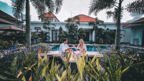 塞隆贝拉纳克Green Valley Lombok的坐在游泳池前的新娘和新郎
