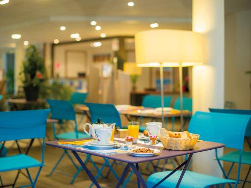 贝诺代阿伟尔花园蓝色假日公寓的一张桌子,上面摆放着食物和饮料,还有蓝色的椅子