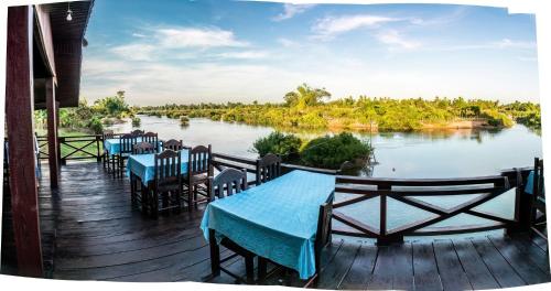 Ban KhonChanhthida Riverside Guesthouse and The River Front Restaurant的河边的甲板上摆放着桌椅