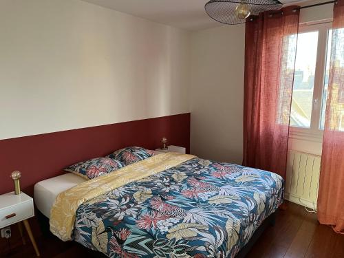 圣布里厄Appartement quartier calme. Proche Port et plages.的一间卧室配有一张带彩色毯子和窗户的床。