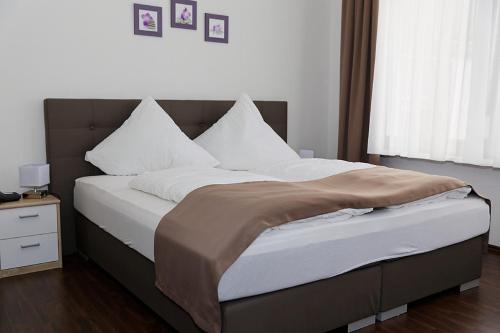 沃尔姆斯Hotel Hüttl - Garni的卧室配有一张带白色床单和枕头的大床。