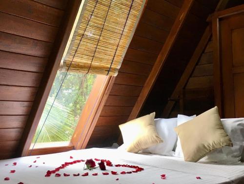 乌纳瓦图纳Sky View Cabin Unawatuna的一张带红色玫瑰花瓣的床,带窗户