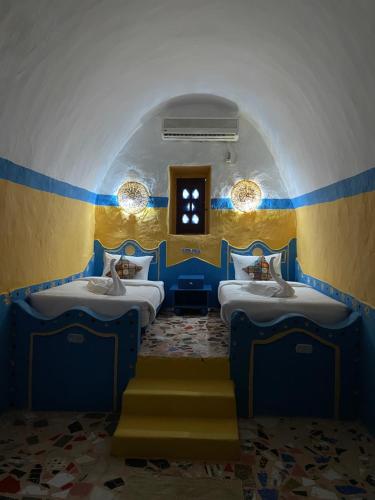 阿斯旺Nubian palace的蓝色和黄色的客房设有三张床