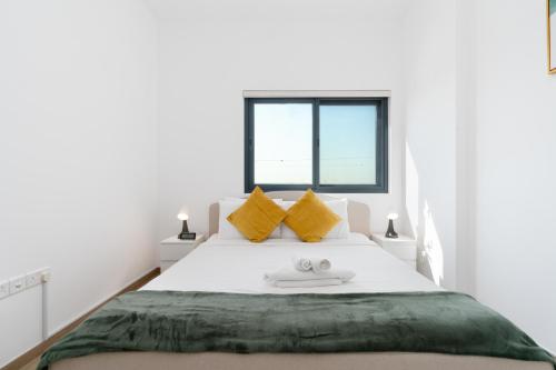 迪拜Lux BnB Nook -2 I City Views的白色卧室配有一张带黄色枕头的大床