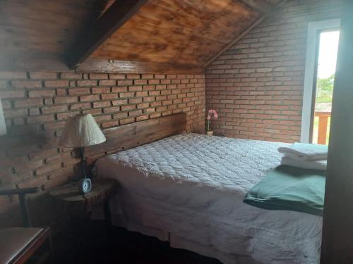 圣托梅-达斯莱特拉斯Ecovalle São Thomé的一间卧室设有砖墙和一张床