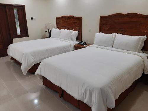 Bon AccordPESHERES INN & SPA的配有白色床单的酒店客房内的两张床